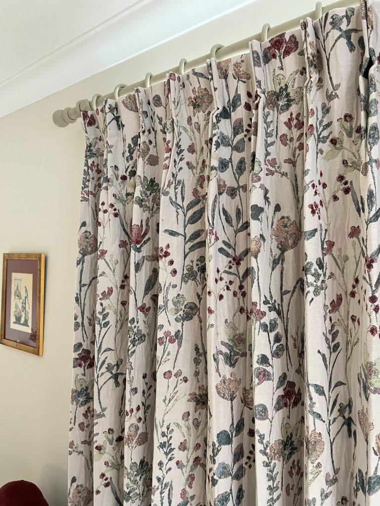 Rideaux sur mesure en tissu à motif floral style aquarelle dans des tons doux, suspendus à une tringle claire, Intérieurs Inspirés.